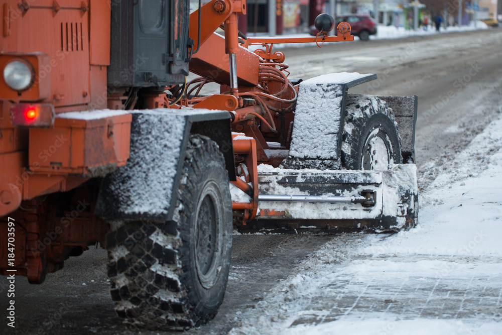 Tractor cleaning the road from the snow. Excavator cleans the streets of large amounts of snow in city. Workers sweep snow from road in winter, Cleaning road from snow storm.