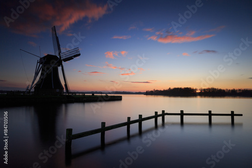 Dutch windmill at a lake during a tranquil dusk.