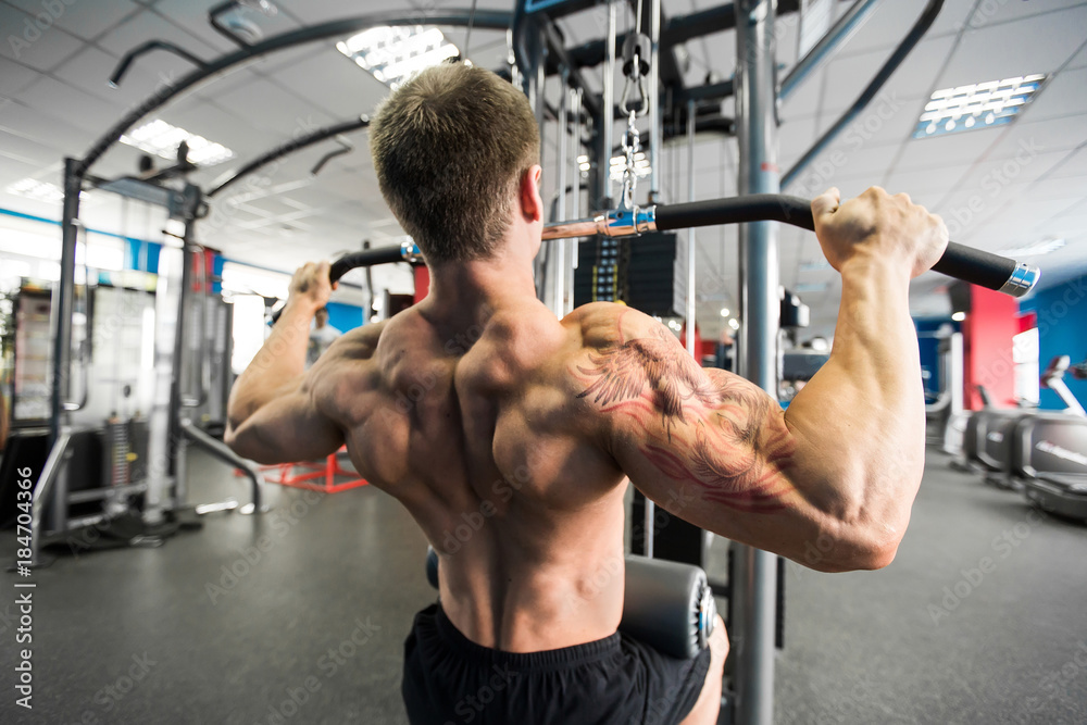 Shoulder pull down machine. Fitness man working out lat pulldown training at gym. Upper body strength exercise for the upper back. Shoulder pull down machine. Fitness man working out lat pulldown training at gym. Upper body strength exercise for the upper back.