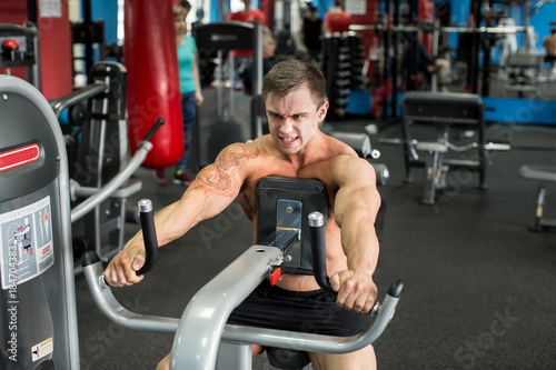 Muscular man working out in gym doing exercises, strong male