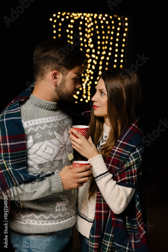 Couple wearing woolen sweaters enjoying a romantic moment while drinking jup of tea in wintertime
