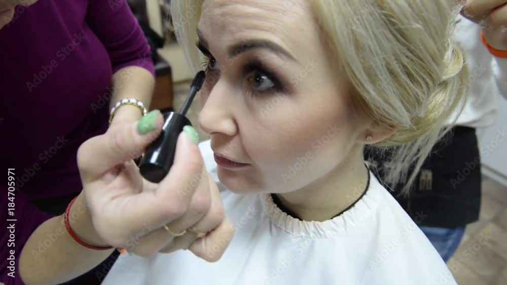 A blond woman in a beauty salon. Make-up artist makes make-up eyelashes in a young woman.Makeup. Cosmetic. Base for Perfect Make-up.Applying Make-up. A blond woman in a beauty salon. Make-up artist makes make-up eyelashes in a young woman.Makeup. Cosmetic. Base for Perfect Make-up.Applying Make-up.