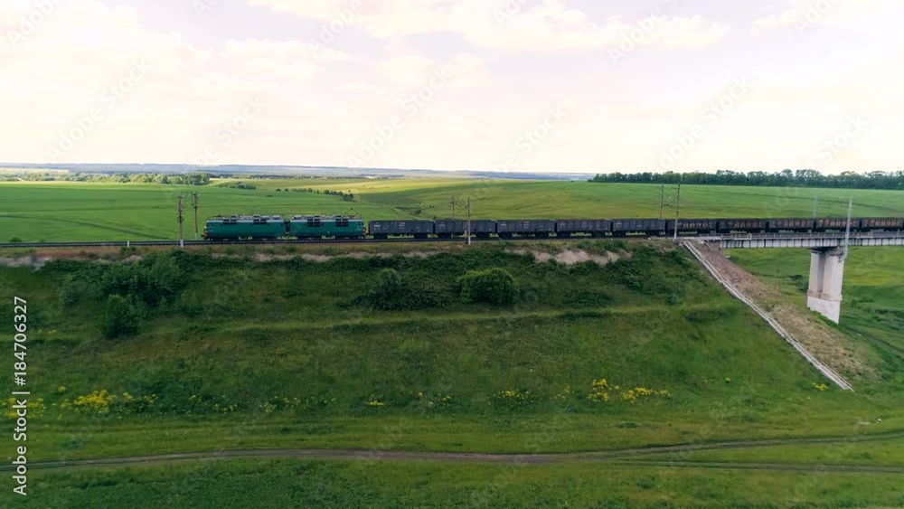 Freight train with many containers crossing railroad bridge. Rail freight transport delivering goods Freight train with many containers crossing railroad bridge. Rail freight transport delivering goods