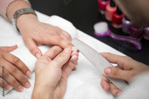 Man manicurist doing manicure for women in beauty salon