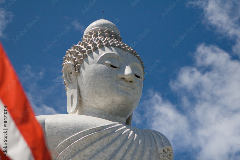 Thailand flag waving over Big Buddha monument and blue cloudy sky Thailand flag waving over Big Buddha monument and blue cloudy sky