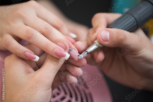 Closeup shot of master uses an electric machine to remove the nail polish during manicure in the salon. Hardware manicure. Concept of body care