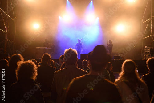 People silhouettes in front of bright stage lights, music