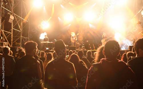People silhouettes in front of bright stage lights,