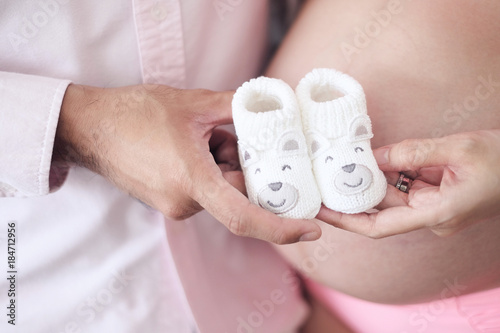 man and pregnant women holding baby shoes