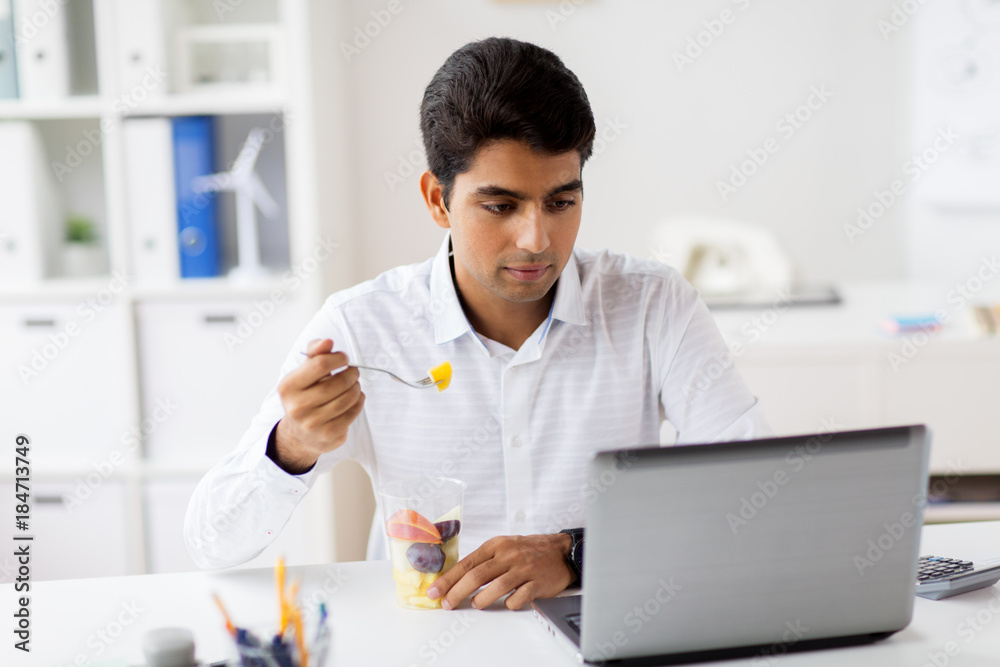 businessman with laptop eating fruits at office