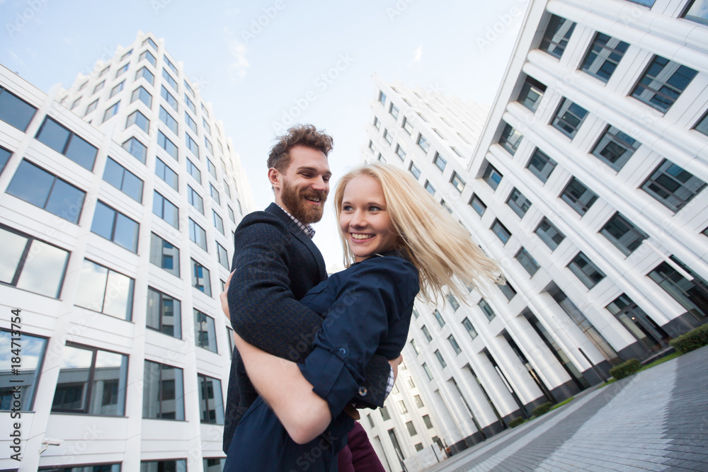 Man and woman hugging and laughing in front of a white building. Bottom view Man and woman hugging and laughing in front of a white building. Bottom view