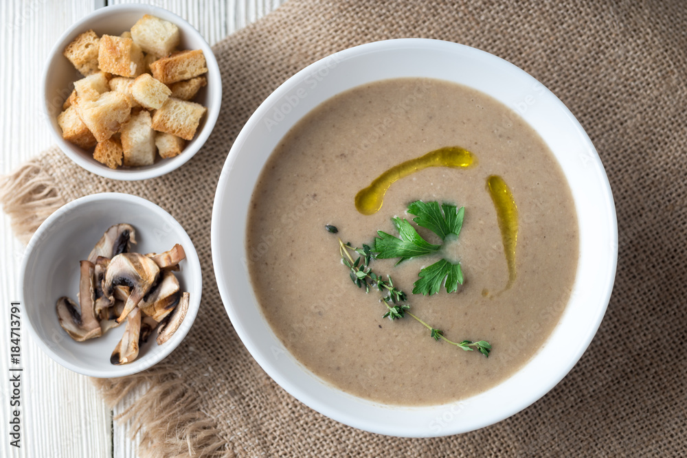 Mushroom cream soup with herbs and spices over rustic wooden background Mushroom cream soup with herbs and spices over rustic wooden background