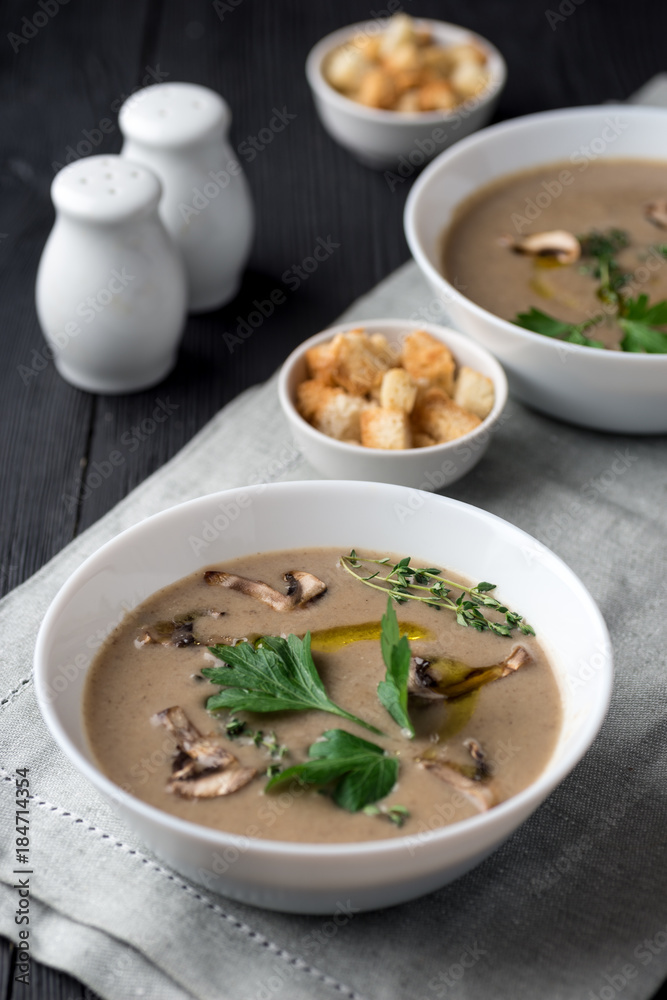 Mushroom cream soup with herbs and spices over rustic wooden background Mushroom cream soup with herbs and spices over rustic wooden background