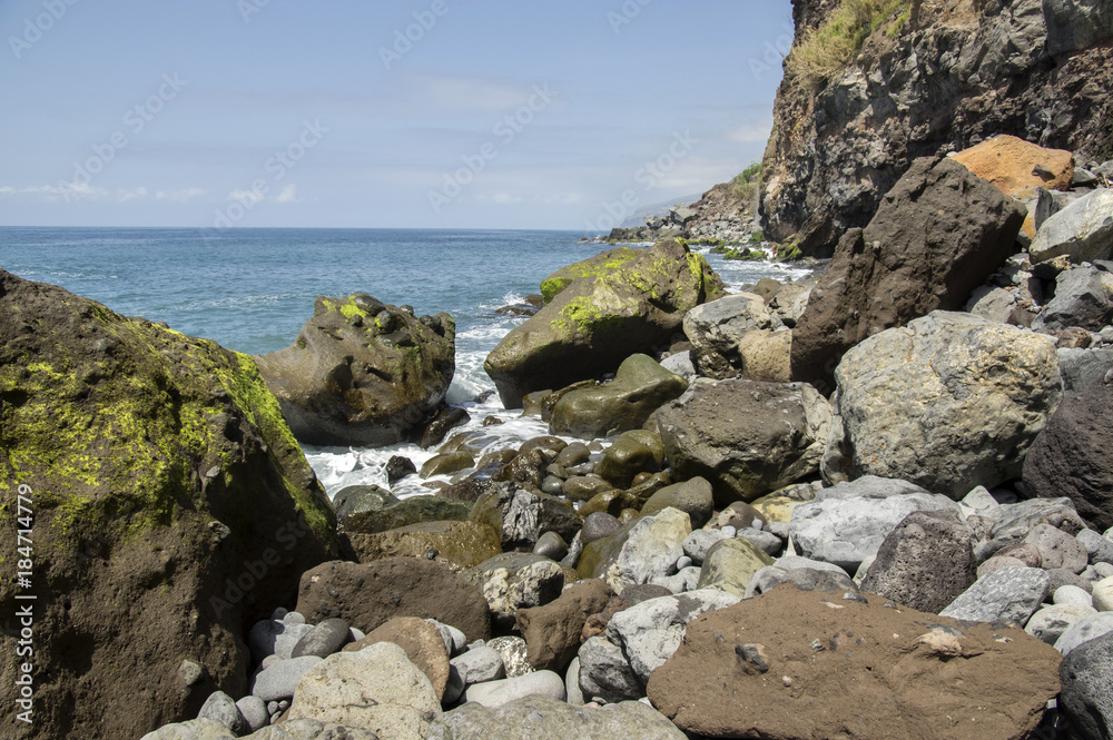 Beach Ponta de Sol rocky green coastline with cliffs and big volcano stones, Madeira island, Portugal