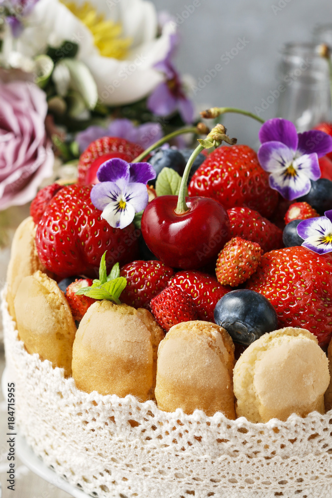 French charlotte cake with summer fruits decorated with pansy flowers.
