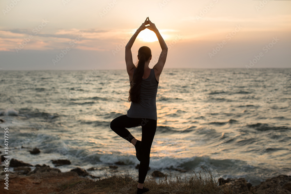 Caucasian woman practicing yoga at seashore of ocean