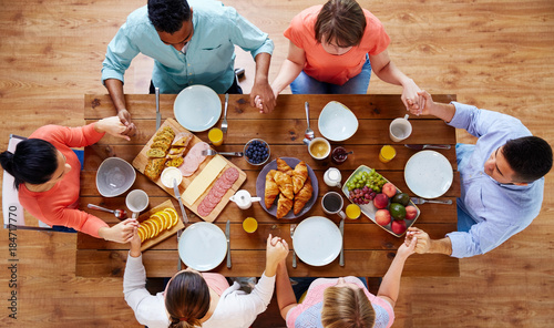 group of people at table praying before meal