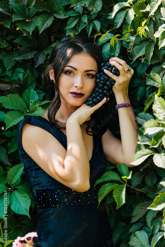Portrait of young sexy brunette with black grapes. Portrait of young sexy brunette with black grapes.