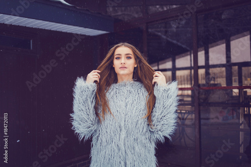 Close-up fashion portrait of gorgeous woman in stylish winter fluffy coat and posing
