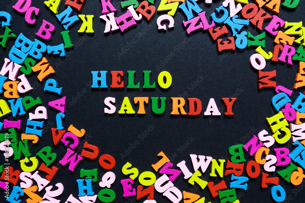 concept design - the word HELLO SATURDAY from multi-colored wooden letters on a black background, creative idea