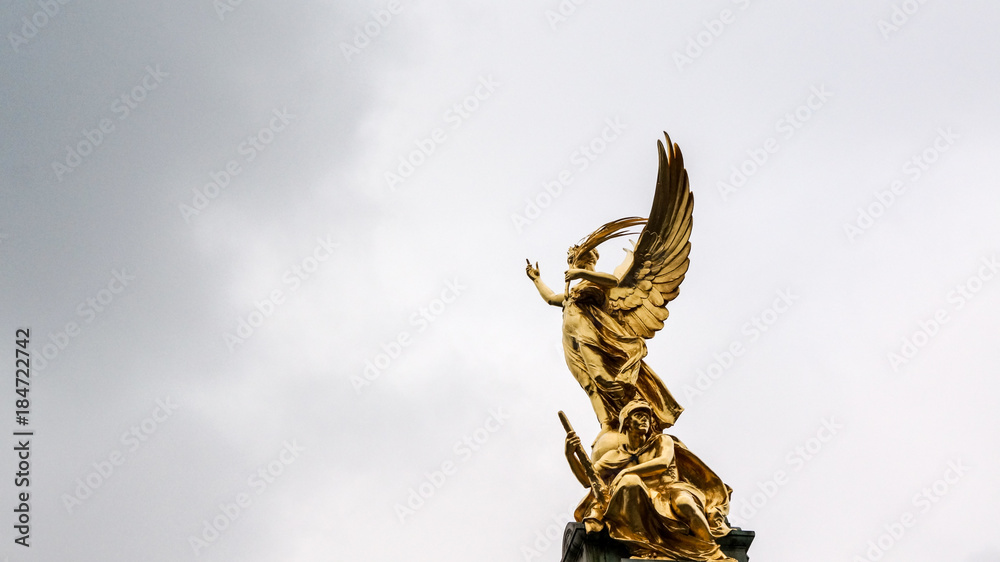 Fototapeta premium Statue of gold angel reaching toward the sky