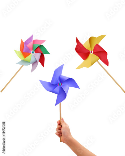 Kid hand holding a blue pinwheel close up and colorful pinwheel on white background.