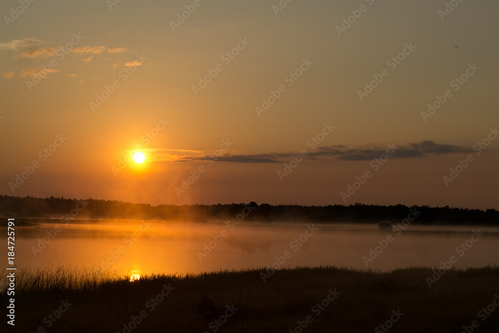 Sunrise by lake at foggy morning