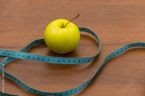 Measuring tape and green apple on wooden table. Concept of diet and healthy lifestyle