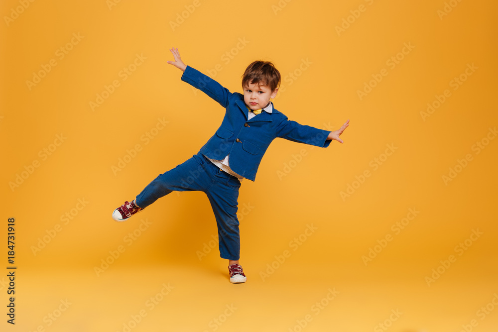 Funny little boy child standing isolated over yellow