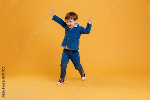 Funny little boy child standing isolated over yellow