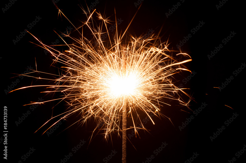 Burning New Year sparkler close up on black background