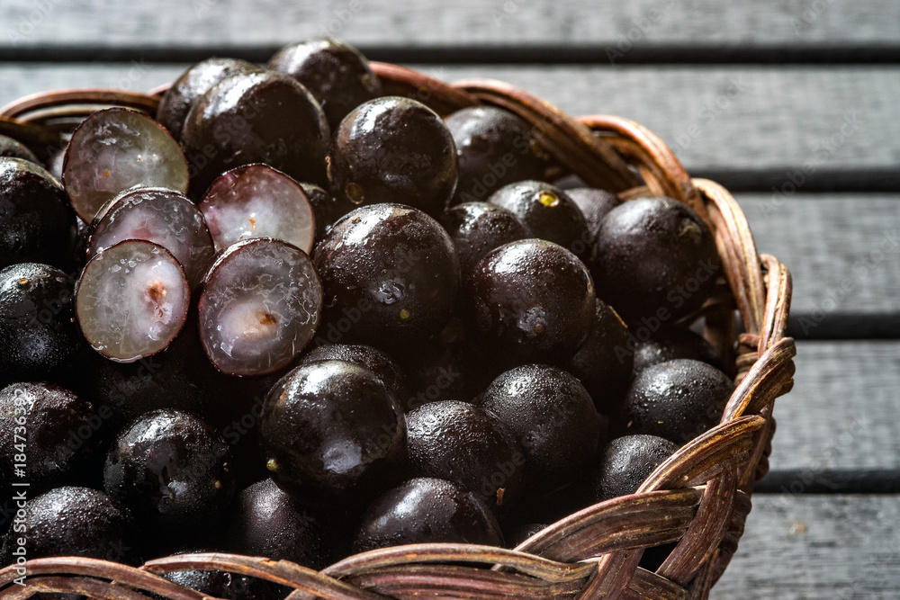 custom made wallpaper toronto digitalJabuticabas, also known as Brazilian Berry or Brazilian Grapetree (Plinia cauliflora) fruits on a wooden vine basket, with a black wooden background wet with water drops
