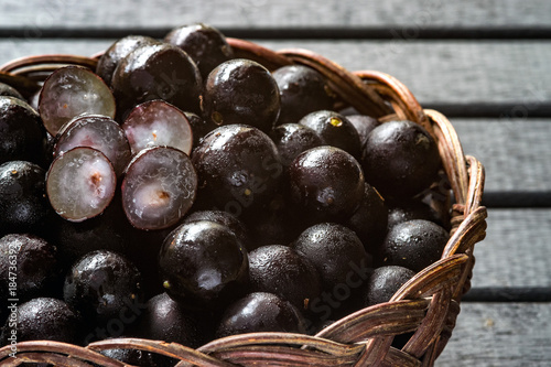 Wallpaper Mural Jabuticabas, also known as Brazilian Berry or Brazilian Grapetree (Plinia cauliflora) fruits on a wooden vine basket, with a black wooden background wet with water drops Torontodigital.ca