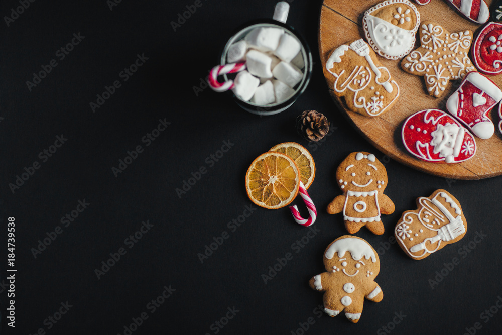 Plate with Christmas cookies on black table with cup of hot chocolate and gifts 