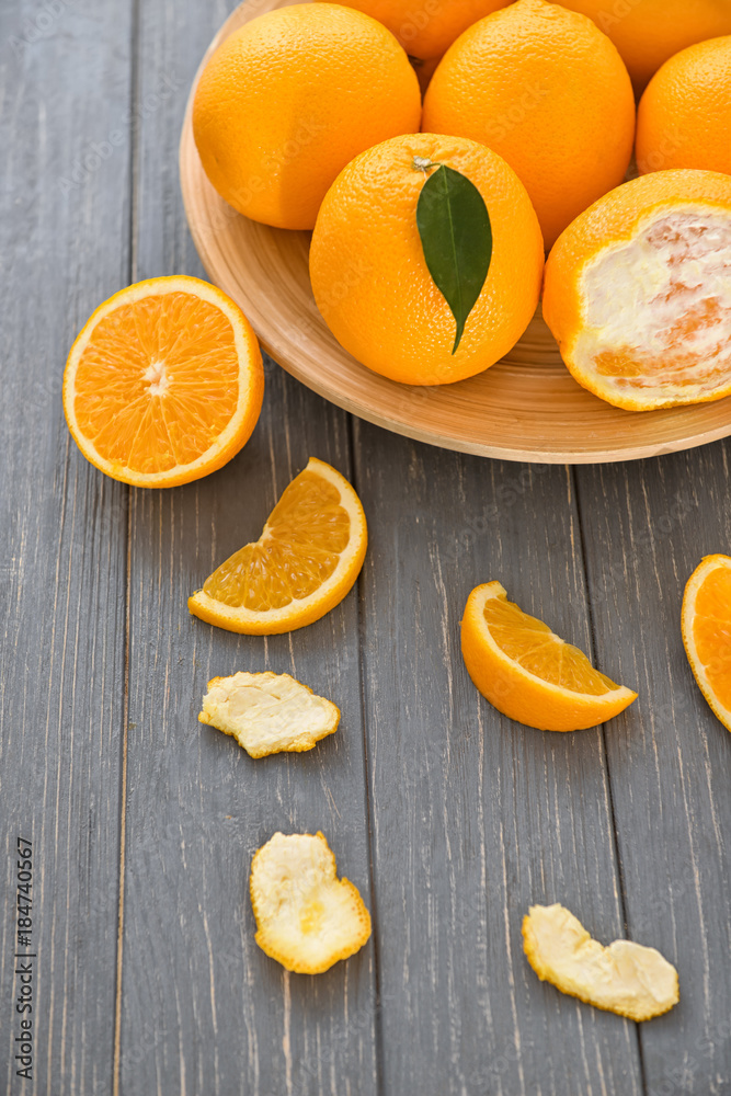 Plate with fresh ripe oranges on wooden table