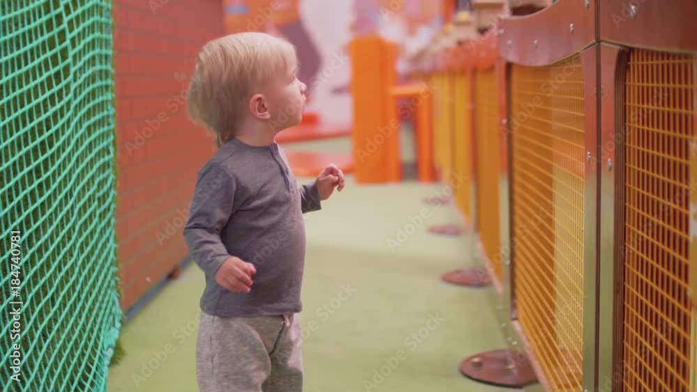 Blond toddler with blue eyes looks at camera with scare and turns his head Blond toddler with blue eyes looks at camera with scare and turns his head