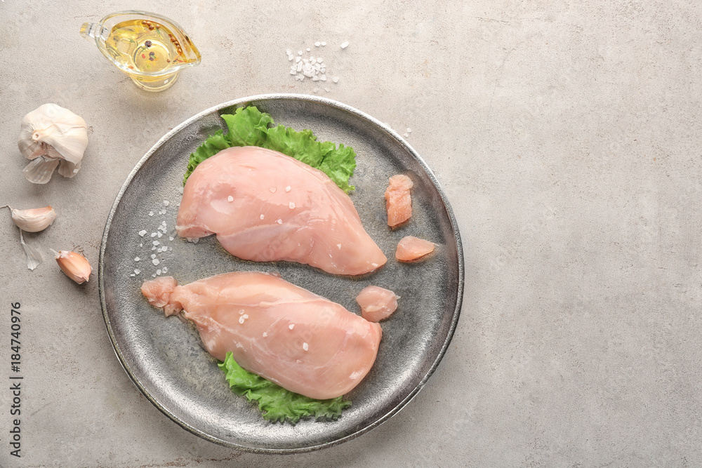Plate with raw chicken fillet on grey background Plate with raw chicken fillet on grey background