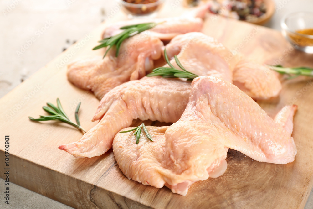 Wooden board with raw chicken wings on table, closeup Wooden board with raw chicken wings on table, closeup