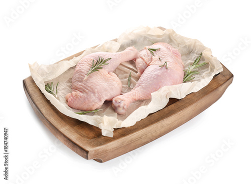 Wooden board with raw chicken legs on white background