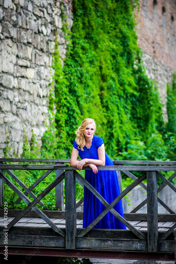 A woman in a blue dress is standing in the park A woman in a blue dress is standing in the park