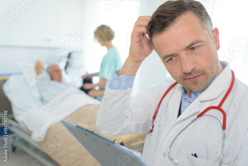 frustrated mature doctor scratching his head in patients room