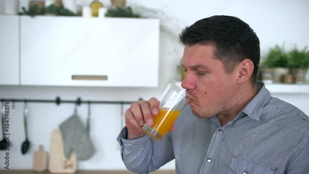 Attractive young man drinking orange juice in a kitchen. Healthy lifestyle. slow-motion Attractive young man drinking orange juice in a kitchen. Healthy lifestyle. slow-motion