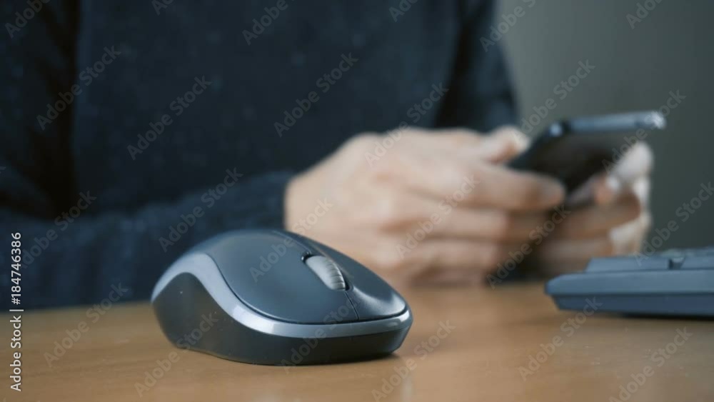 Hand of a man working at computer and using smartphone Hand of a man working at computer and using smartphone