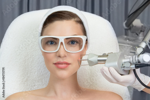 Therapist beautician makes a  laser rejuvenation for the model by  apparatus  in a beauty salon. photo