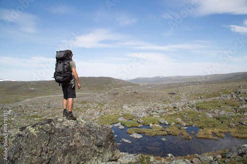 Hiker stands on a rock, view from southwest towards the nature reserve Ráisduottarháldi, near Guolasjávri, Haltitunturi, summer  photo