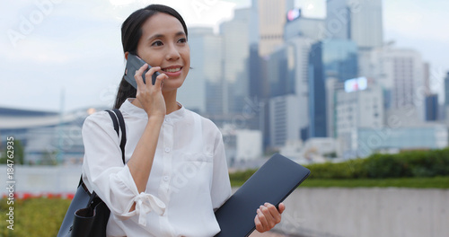 Photography Woman talks on cellphone and holds notebook in city
