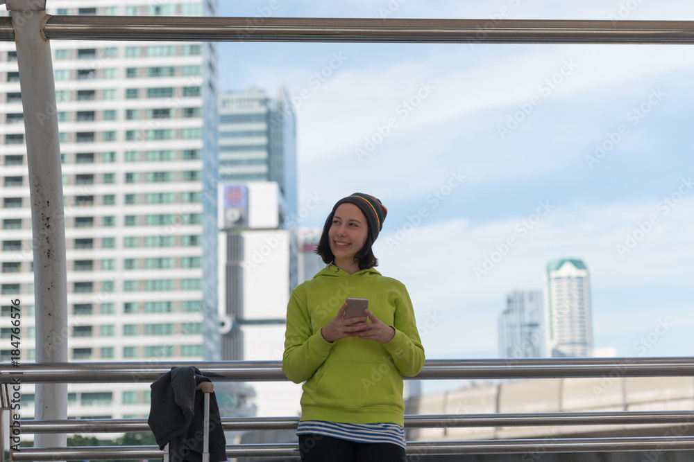 Happy traveler using a smartphone in city building while is waiting for transport