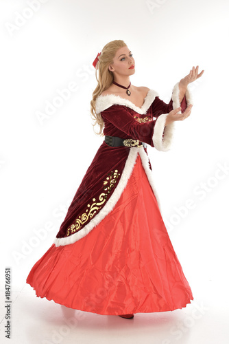 full length portrait of pretty blonde lady wearing red and white christmas inspired costume gown  standing pose on white background.