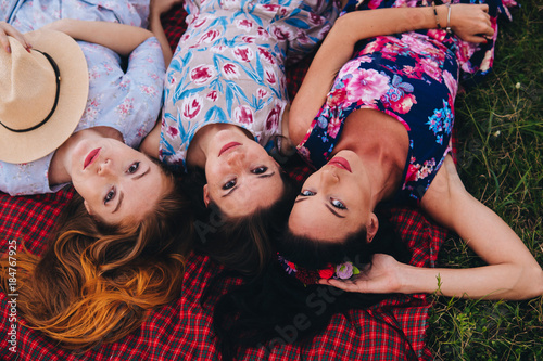 Women lay on grass during picnic in the countryside - Three girls on vacation