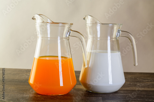 two jars one with milk other with orange juice photo